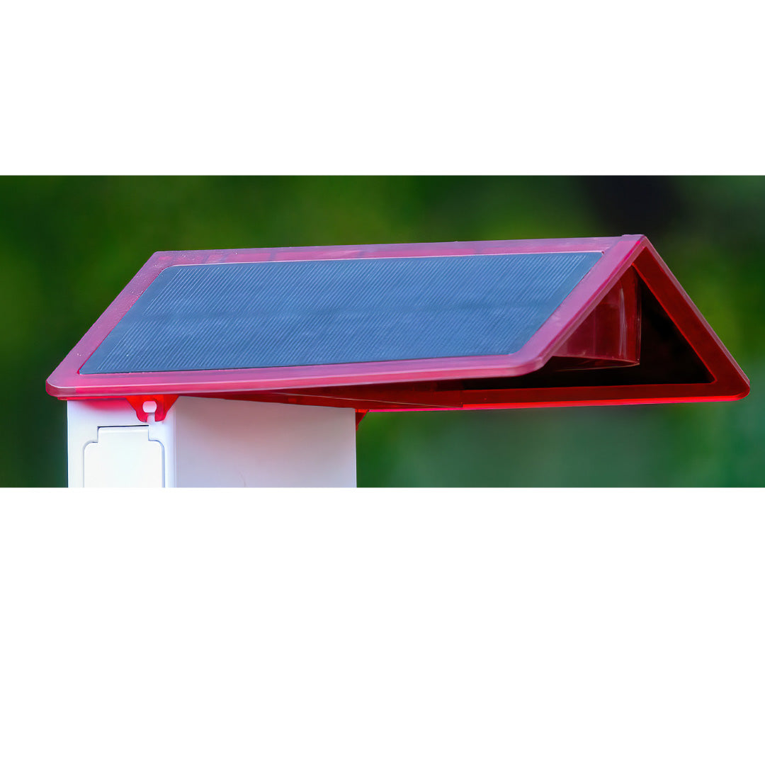 Red roof with black solar panels attached to smart hummingbird feeder on a green background